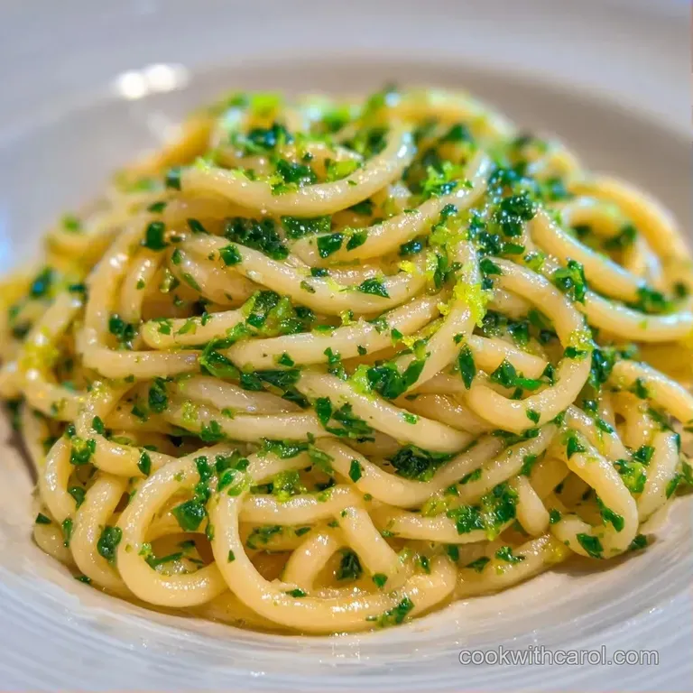 Al dente pasta in a white ceramic bowl topped with a fresh lemon wedge and delicate shavings of parmesan cheese.