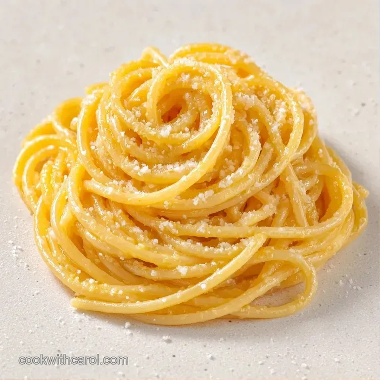 Elegant white bowl of buttery pasta topped with bright zest and a lemon wedge on a neutral linen tabletop.